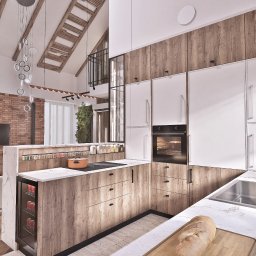 To Oni Projektują - Nowoczesna kuchnia w stylu loft z drewnianymi akcentami, białymi szafkami i marmurowym blatem. Widoczny fragment salonu z ceglaną ścianą i drewnianą podłogą.