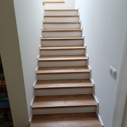 Zakład Stolarski StyloveWood Maciej Grabowski - Proste, nowoczesne schody drewniane z białymi podstopnicami w jasnym wnętrzu. Naturalne drewno stopni kontrastuje z bielą ścian i minimalistycznym stylem.