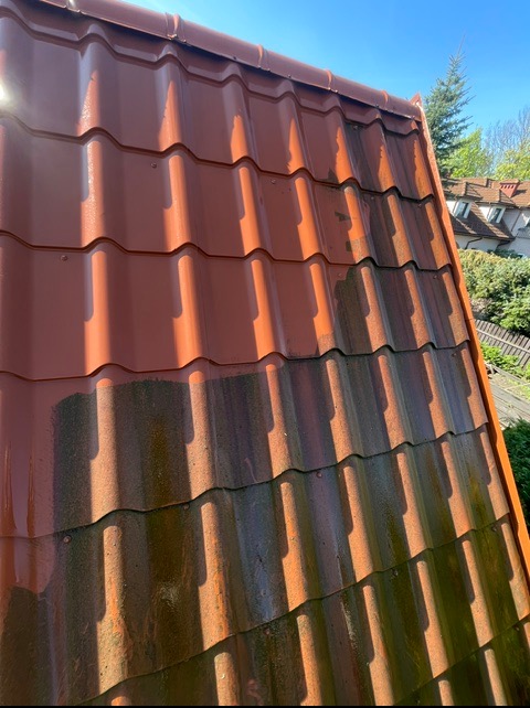 Częściowo wyczyszczony, czerwony dach z dachówki ceramicznej, widoczne różnice w kolorze i czystości. Połowa dachu umyta, druga pokryta mchem i zabrudzeniami.