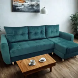 Szmaragdowa sofa narożna z aksamitną tapicerką, ustawiona w jasnym salonie z drewnianą podłogą i stolikiem kawowym z filiżankami.