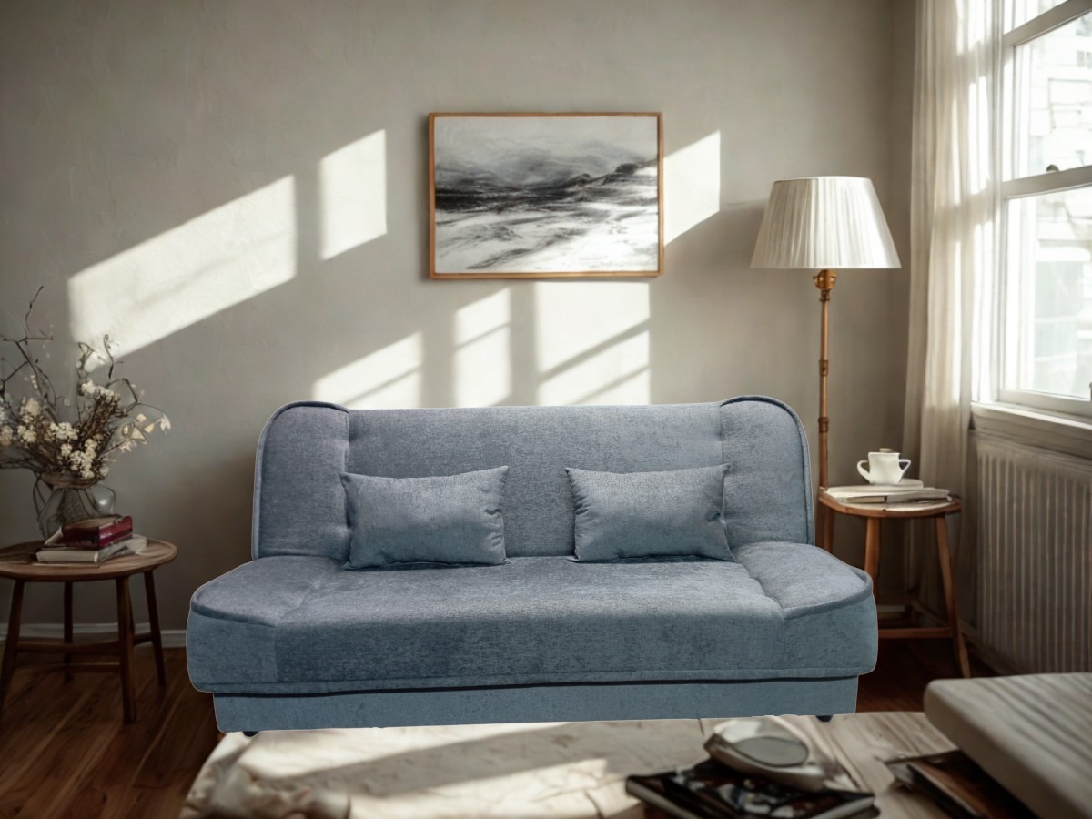 Rozkładana sofa w odcieniach szarości, z poduszkami, w jasnym pokoju z obrazem na ścianie i lampą podłogową. Minimalistyczny design z elementami retro.