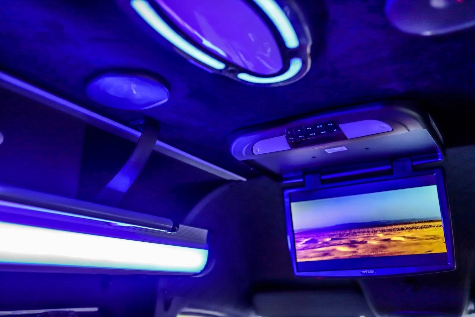 Wnętrze luksusowego pojazdu z oświetleniem LED i ekranem odtwarzającym krajobraz. Komfortowa podróż z rozrywką dla pasażerów.