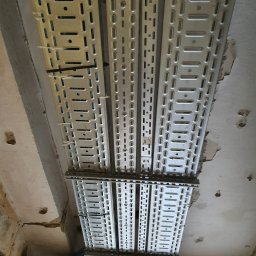 3xNC elektro - Metalowe korytka kablowe zamontowane do sufitu w surowym stanie, widoczne przewody zabezpieczone opaskami. Instalacja elektryczna w trakcie realizacji.