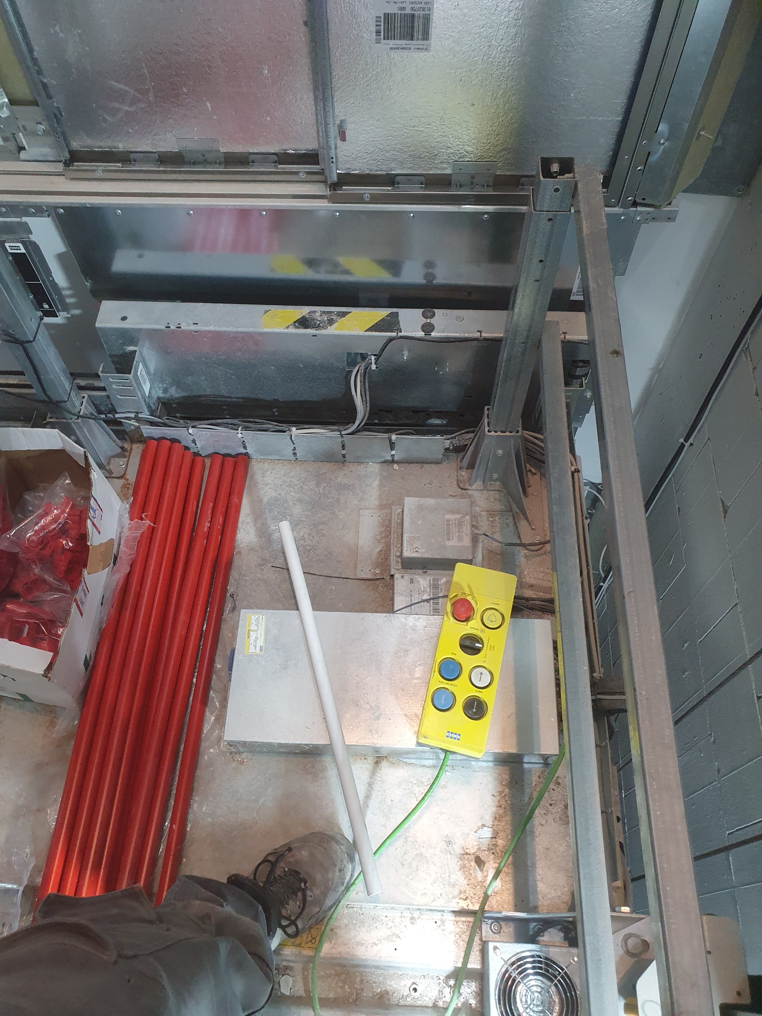 Wnętrze szybu windowego w trakcie prac instalacyjnych. Widoczne elementy konstrukcyjne, przewody elektryczne, rury w izolacji i panel sterowania.