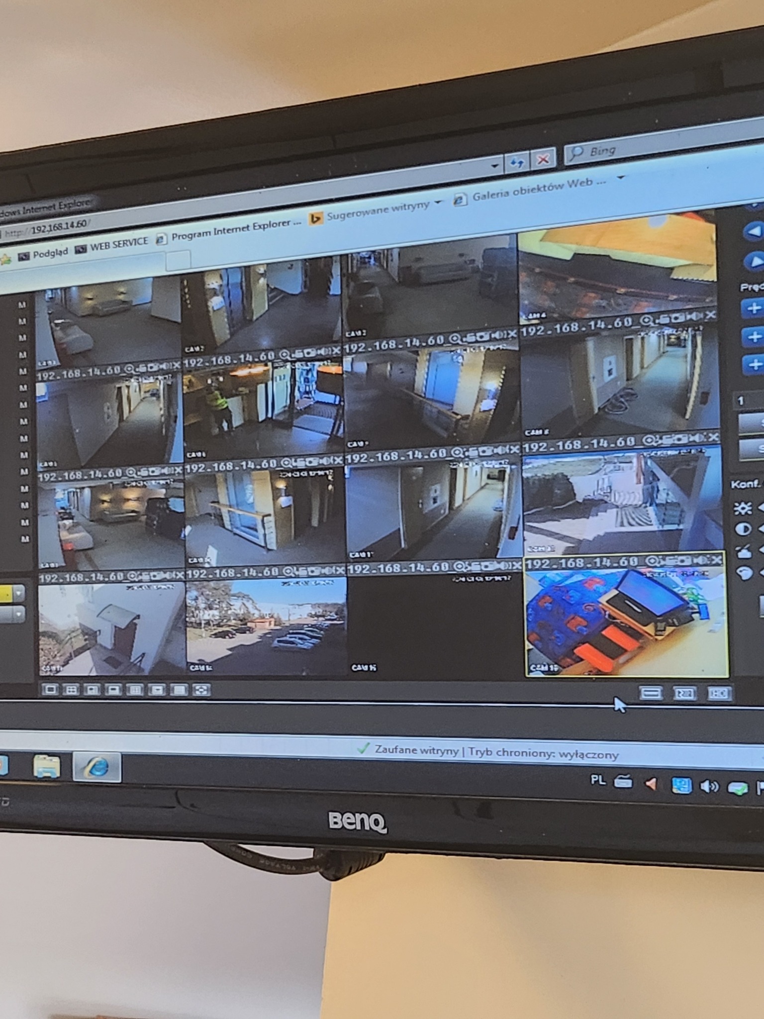 Monitor BenQ wyświetla podgląd z kamer monitoringu, ukazując korytarze, parking i inne obszary. Widok z wielu kamer w jednym oknie przeglądarki.