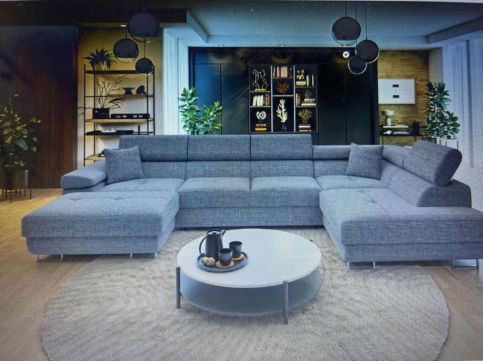 Szary, modułowy narożnik z poduchami i metalowymi nóżkami, na tle nowoczesnego salonu z regałami i okrągłym stolikiem kawowym.