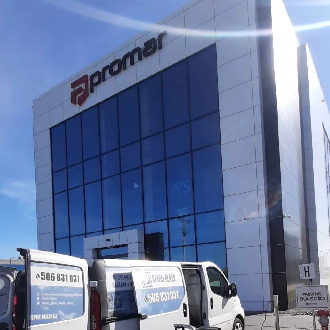 Nowoczesny biurowiec Promar z dużymi, czystymi oknami, odbijającymi niebo. Na pierwszym planie samochody Clean Glass z numerem telefonu i logo firmy.