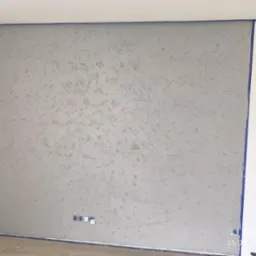 Ściana z efektem dekoracyjnym, zabezpieczona taśmą malarską. Widoczne puszki elektryczne. Szara, teksturowana powierzchnia. Świeżo położona gładź dekoracyjna.