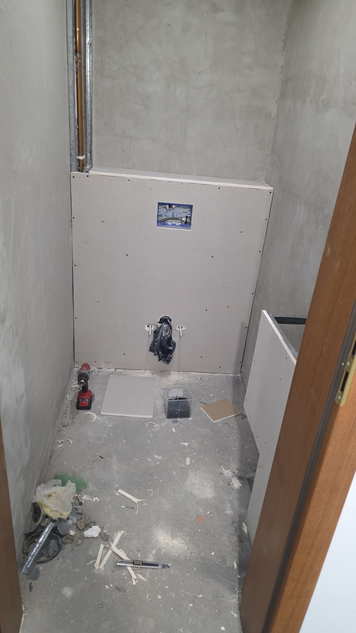 Łazienka w trakcie remontu: ściany z płyt karton-gips, widoczne rury, narzędzia i materiały budowlane. Przygotowanie do wykończenia.