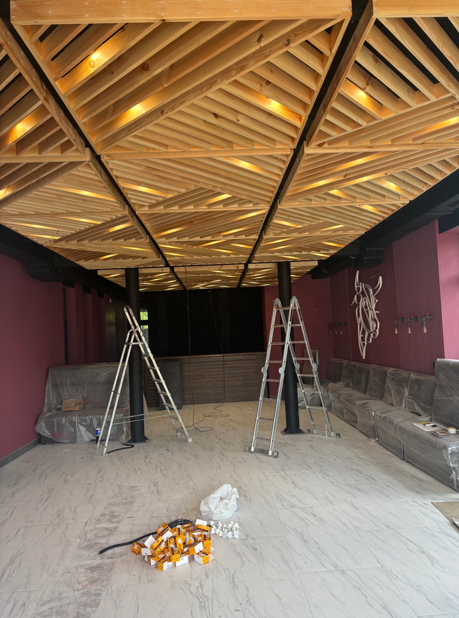 Wykończenie wnętrza: drewniany sufit kasetonowy z oświetleniem, drabiny, sofy zakryte folią i kartony na podłodze. Wnętrze w trakcie prac wykończeniowych.