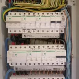 Rozdzielnia elektryczna z zainstalowanymi bezpiecznikami Schneider Electric, opisane obwody, kable w peszlach, widok z bliska.