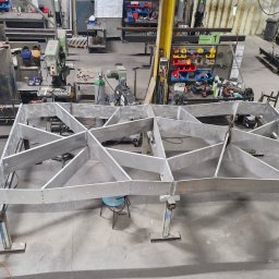 WELT Paweł Brak - Metalowa konstrukcja szkieletowa z profili, spawana, na stojakach w hali produkcyjnej. Widok z góry, butla z gazem w lewym dolnym rogu.