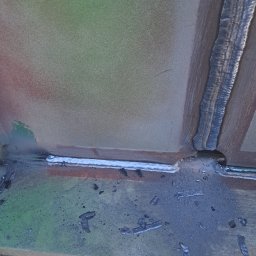 WELT Paweł Brak - Spoina łącząca metalowe elementy konstrukcji. Widoczne ślady po spawaniu i nierówności powierzchni, co sugeruje proces łączenia elementów stalowych.