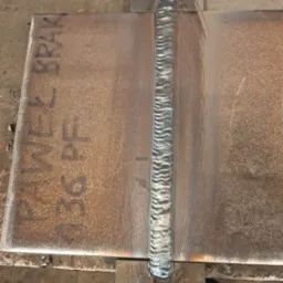 Spoina łącząca dwie metalowe płyty, widoczne ślady po procesie spawania i oznaczenia na metalu, ukazujące precyzję wykonania.