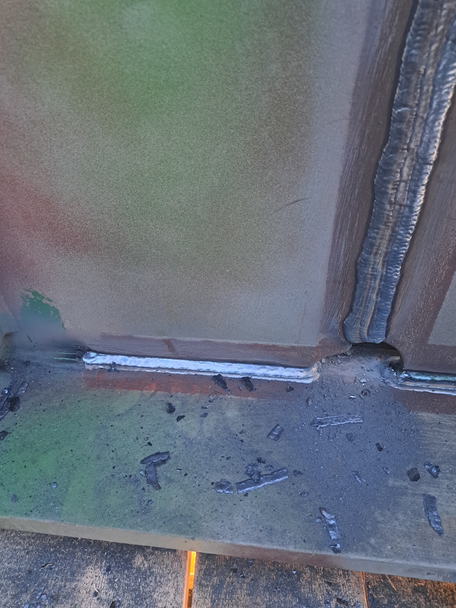 Spoina łącząca metalowe elementy konstrukcji. Widoczne ślady po spawaniu i nierówności powierzchni, co sugeruje proces łączenia elementów stalowych.