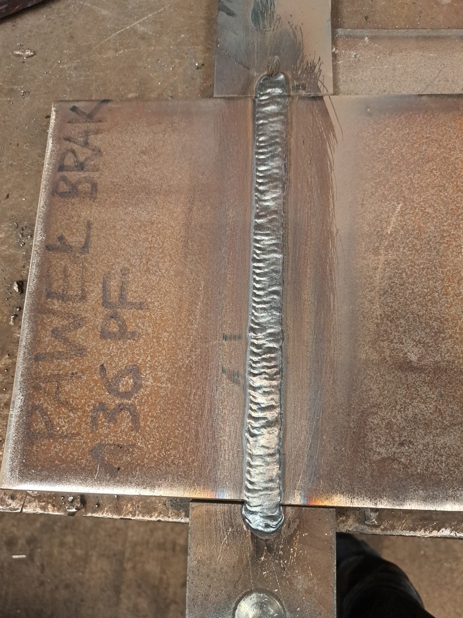 Spoina łącząca dwie metalowe płyty, widoczne ślady po procesie spawania i oznaczenia na metalu, ukazujące precyzję wykonania.