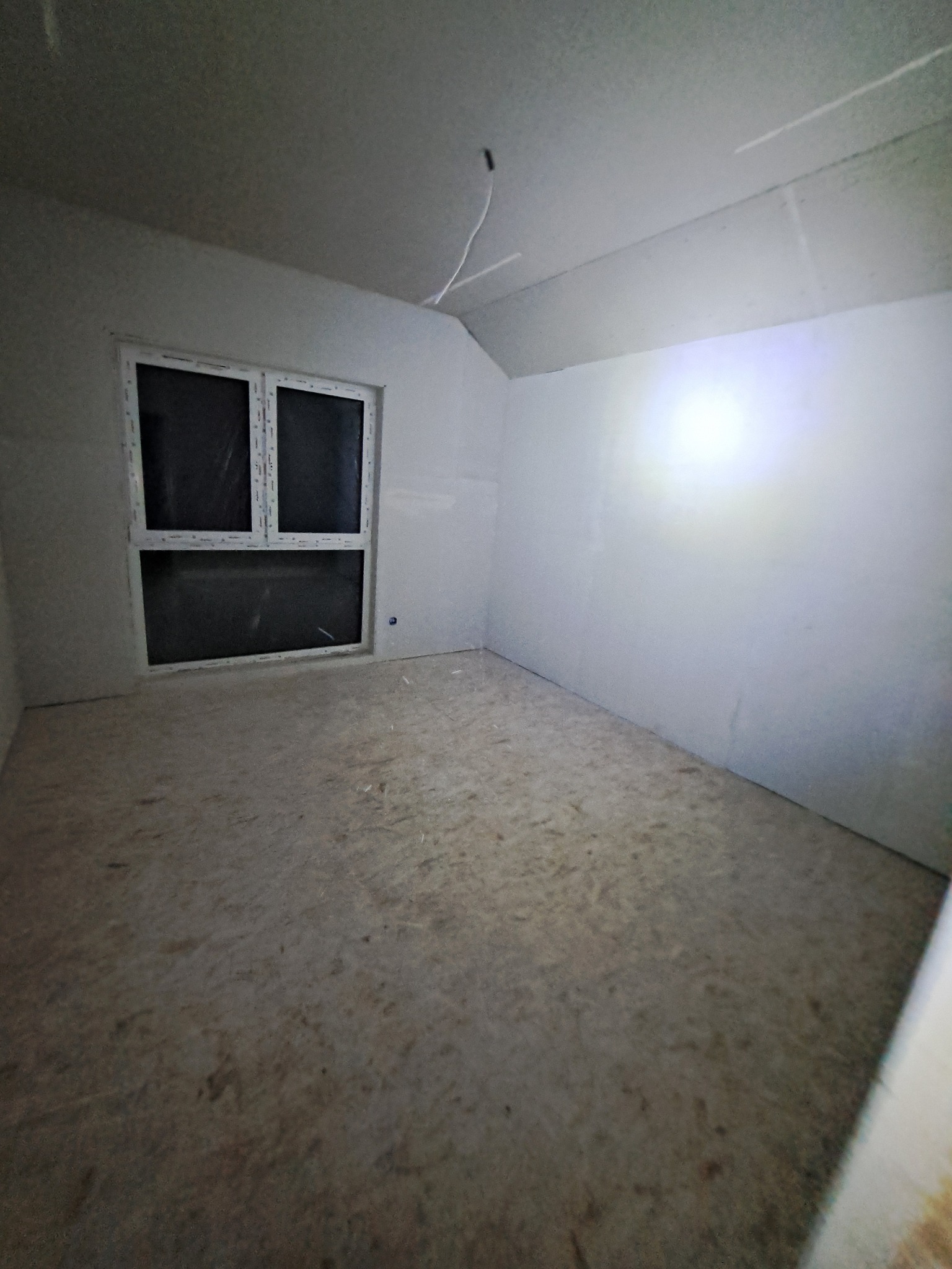 Pokój po montażu płyt kartonowo-gipsowych na ścianach i suficie, widoczne okno. Podłoga surowa, przygotowana do dalszych prac wykończeniowych.