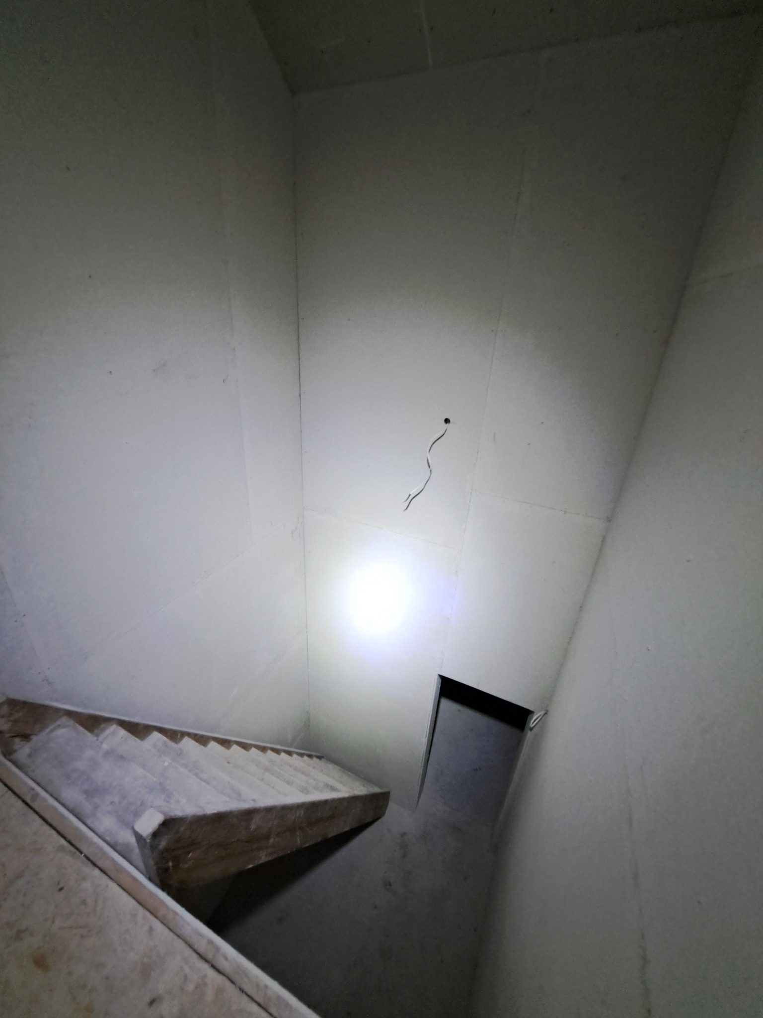 Sufit z płyt kartonowo-gipsowych w trakcie montażu, widoczne przewody elektryczne i fragment schodów. Oświetlenie punktowe podkreśla strukturę płyt.