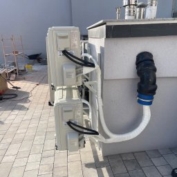 JERZY FRANK HYDROPROJEKT - Montaż klimatyzacji multi split na dachu budynku w Imielinie. Widoczne jednostki zewnętrzne i rury instalacyjne. W tle drabina i narzędzia.