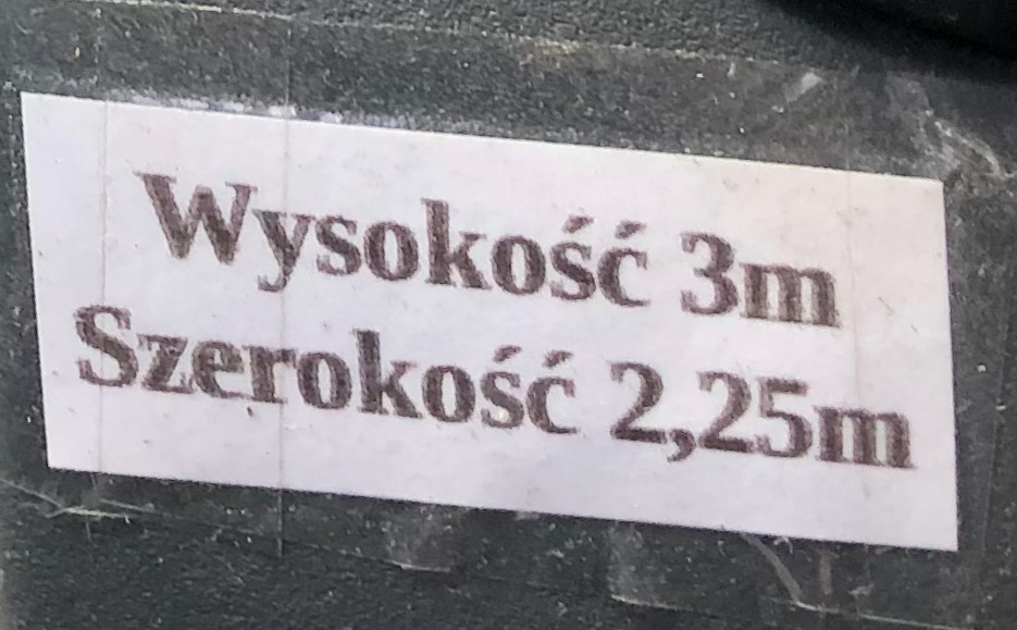 Etykieta z wymiarami: wysokość 3m, szerokość 2,25m, przyklejona do ciemnej powierzchni. Informacja o gabarytach w kontekście przeprowadzki.