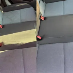 Tapicerka samochodowa tylnej kanapy: widok przed i po czyszczeniu, wyraźna różnica w czystości i odcieniu szarości materiału.