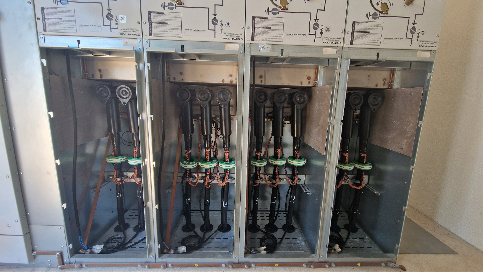 Głowice kablowe 30kV SN w stacji transformatorowej na farmie fotowoltaicznej. Widoczne cztery sekcje z zainstalowanymi głowicami i kablami.