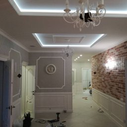 INSIDE_HOME SPÓŁKA Z OGRANICZONĄ ODPOWIEDZIALNOŚCIĄ - Eleganckie wykończenie wnętrza w Gdańsku: dekoracyjne sztukaterie, oświetlenie sufitowe LED i ściana z cegły, tworzące unikalny efekt wizualny.
