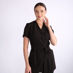 ATORDO DOROTA RYCHWALSKA - Kobieta prezentuje czarny, wiązany uniform medyczny z krótkim rękawem na białym tle. Elegancki i profesjonalny strój dla personelu medycznego.