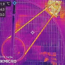 Termowizja silnika wentylatora w obudowie kratowej, z zaznaczonymi zakresami temperatur. Diagnostyka termowizyjna wskazuje na potencjalne przegrzewanie się elementu.