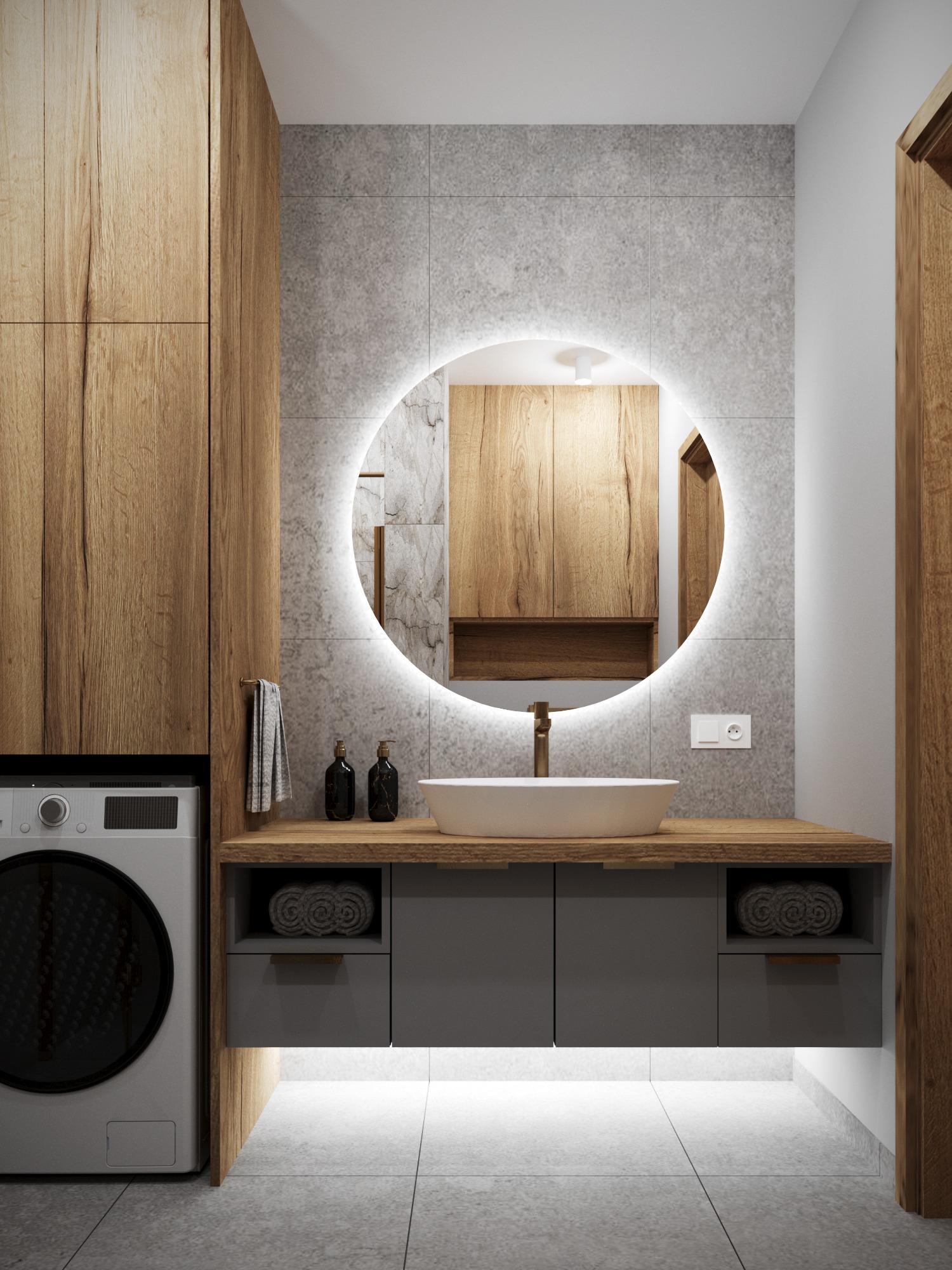 Nowoczesna łazienka z okrągłym lustrem z podświetleniem LED, drewnianymi szafkami i szarą umywalką nablatową. Minimalistyczny design z pralką w zabudowie.