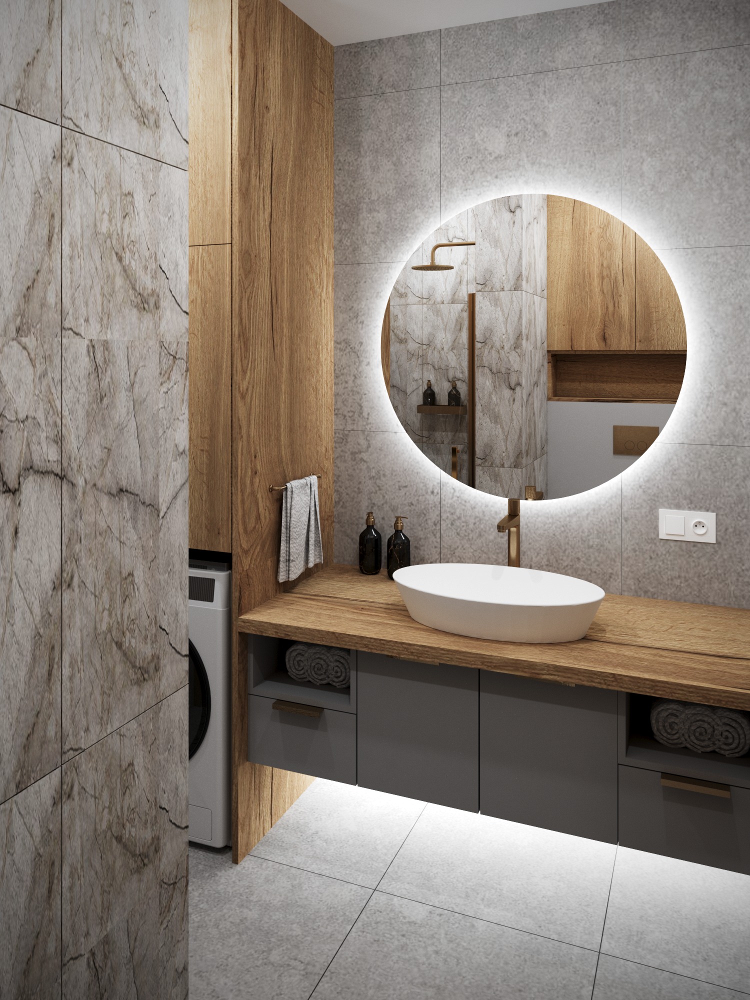 Nowoczesna łazienka: okrągłe lustro z podświetleniem, drewniany blat z umywalką, szare szafki i marmurowe płytki. Pralka schowana za ścianką.