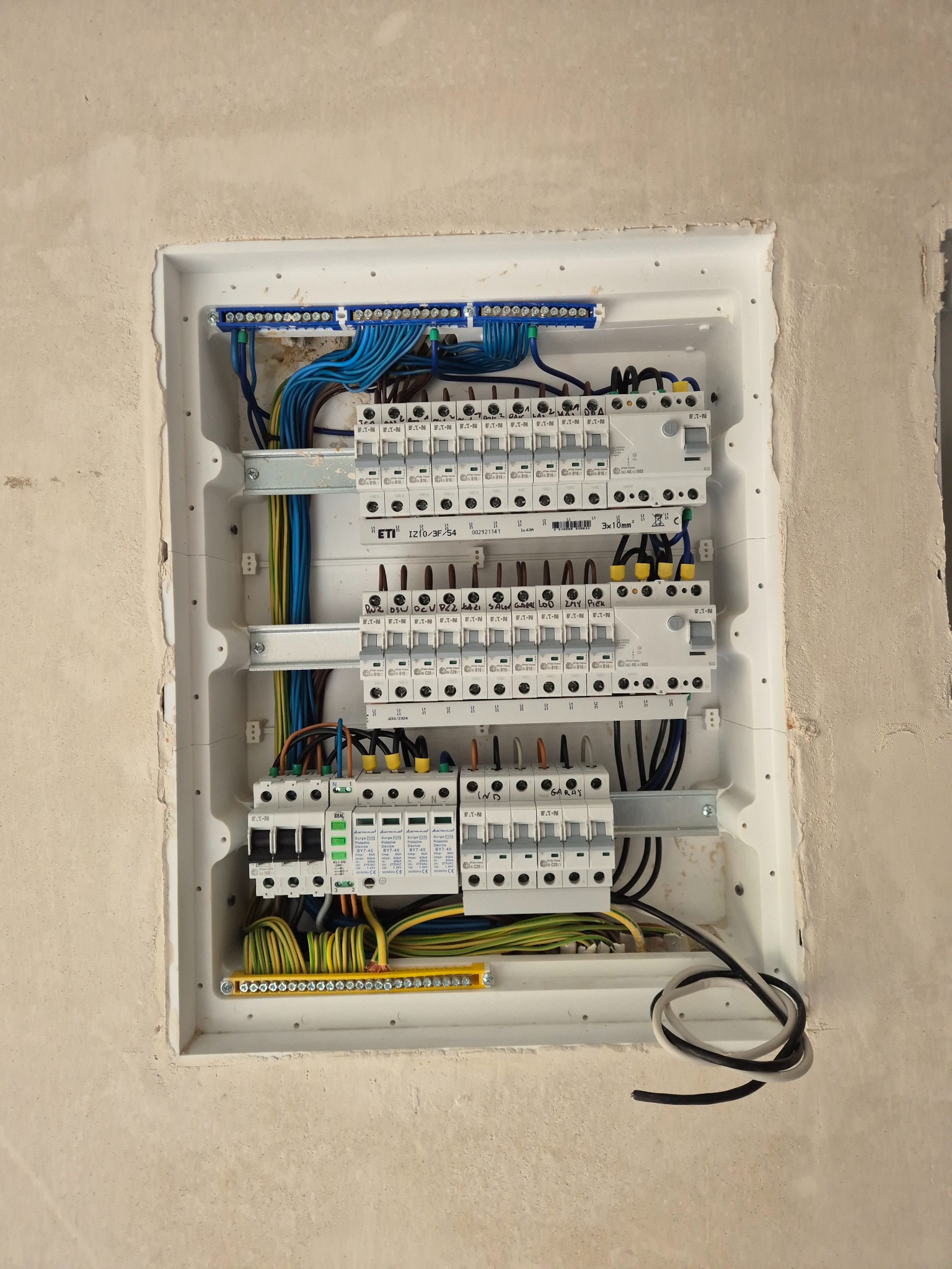 Rozdzielnia elektryczna wnękowa z zainstalowanymi zabezpieczeniami, przewodami i listwami, umieszczona w surowej ścianie, gotowa do podłączenia.
