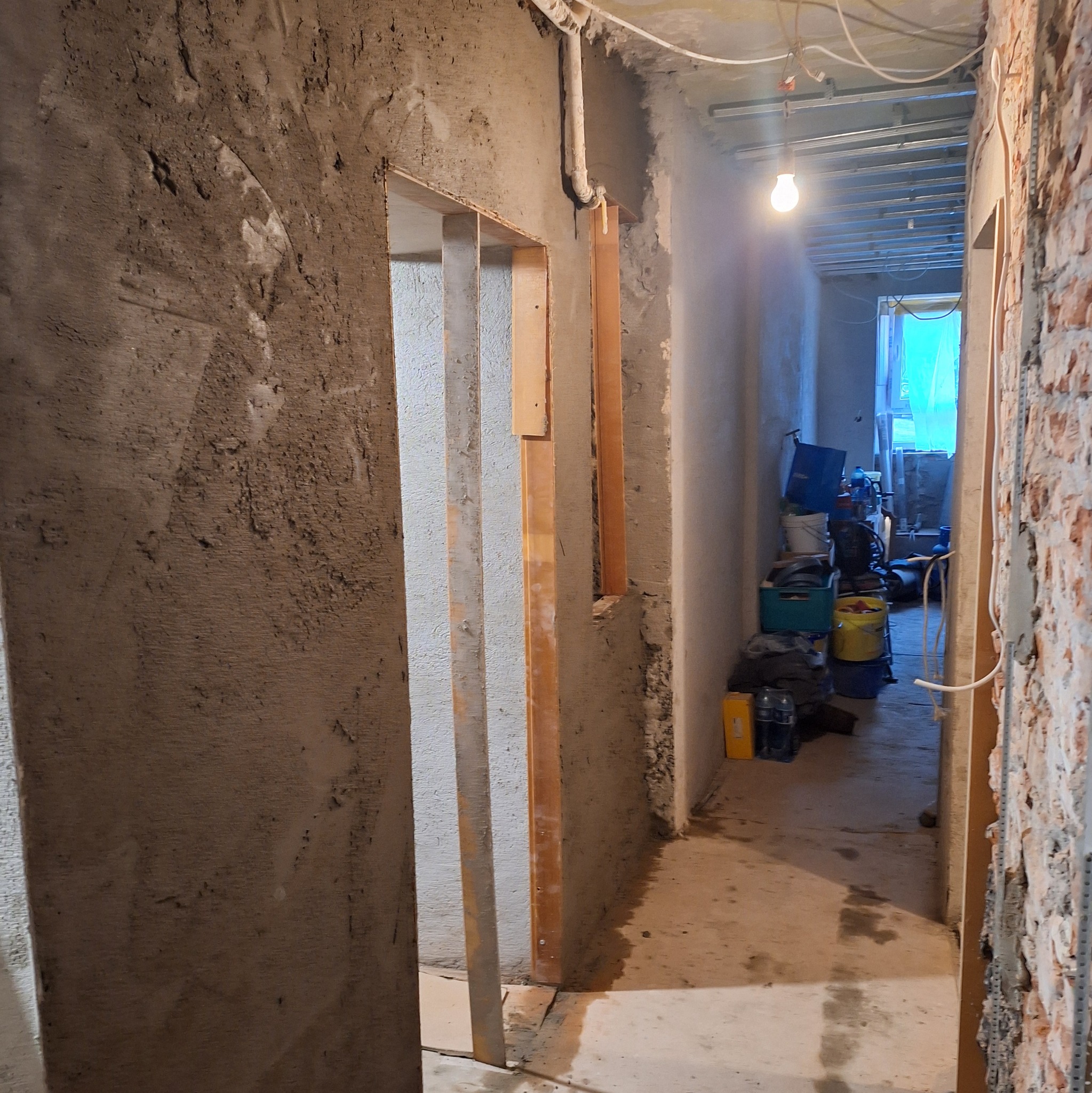 Wnętrze w trakcie remontu w Gryfowie Śląskim. Widoczne surowe ściany, drewniane ramy drzwiowe i instalacja podwieszanego sufitu. Prace remontowe w toku.