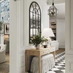 Mala & Co. Malwina Wilczek - Elegancki hol z konsolą, lustrem w stylu industrialnym i wzorzystą podłogą. Lampa stołowa i rośliny dodają przytulności. Widok na salon z obrazem konia.