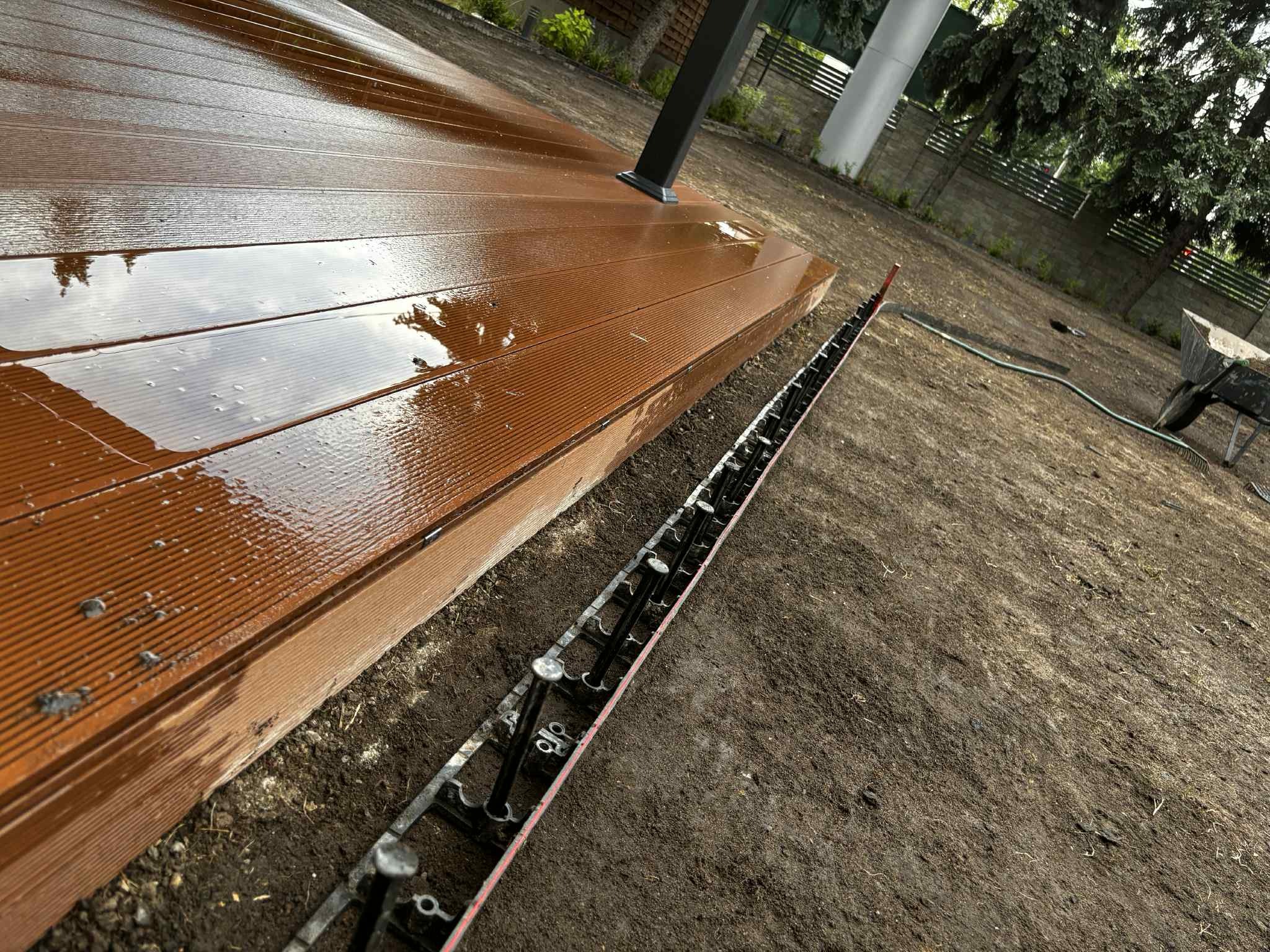 Montaż brązowego tarasu kompozytowego na regulowanych wspornikach. Widoczne elementy konstrukcyjne i przygotowane podłoże.