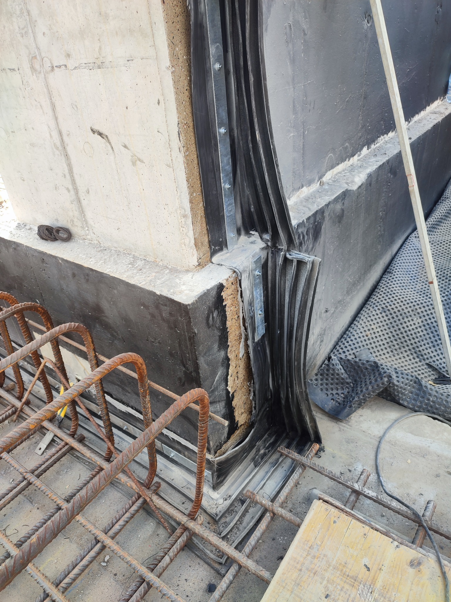 Szczegółowe ujęcie dylatacji pionowej w konstrukcji betonowej, z widocznym uszczelnieniem i elementami zbrojenia. Widoczne materiały izolacyjne i hydroizolacyjne.