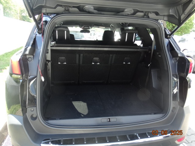 Otwarty bagażnik czarnego SUV-a, widok z tyłu, wnętrze puste, gotowe do załadunku. Widoczne tylne siedzenia i elementy wykończenia bagażnika.