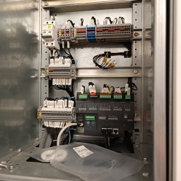 VIKTORISERVIS Stanisław Bohodukh - Wnętrze szafy sterowniczej z widocznymi elementami instalacji elektrycznej: bezpieczniki, listwy zaciskowe, kable z oznaczeniami i sterownik. Widoczne złącza ethernet.