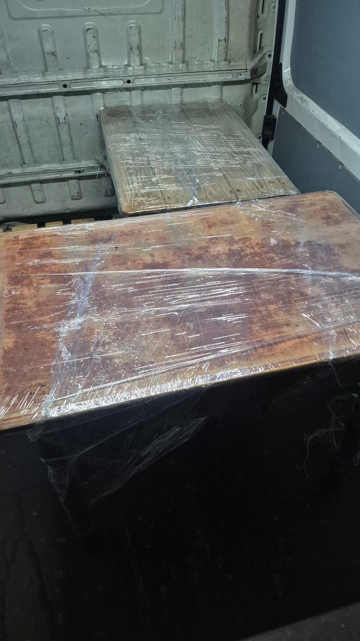 Meble zabezpieczone folią w przestrzeni ładunkowej busa podczas transportu w Warszawie. Widoczne elementy wnętrza pojazdu dostawczego.