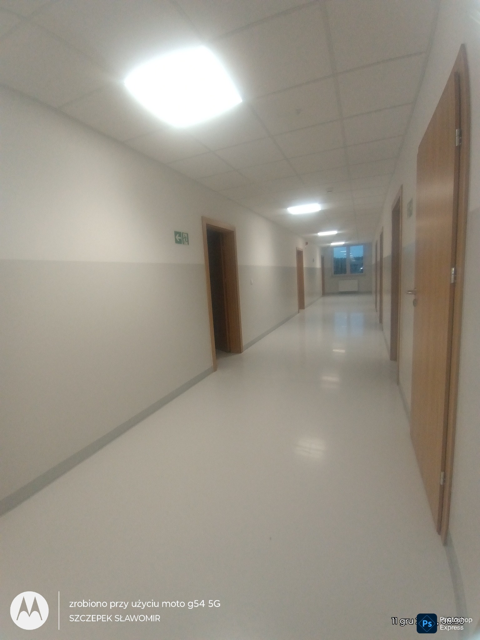 Korytarz po remoncie: świeżo pomalowane ściany w odcieniach bieli i szarości, jasna podłoga, drewniane drzwi i energooszczędne oświetlenie sufitowe.