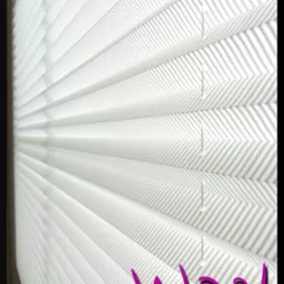 Biała plisa okienna z delikatnym szarym wzorem w paski, zamontowana w oknie. Widoczne detale konstrukcji i fałdy materiału. U dołu logo firmy.