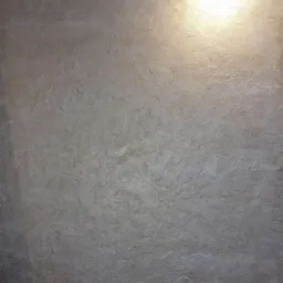 Beżowa ściana z fakturą, oświetlona od góry, z kratką wentylacyjną w rogu. Tekstura ściany przypomina naturalny kamień.