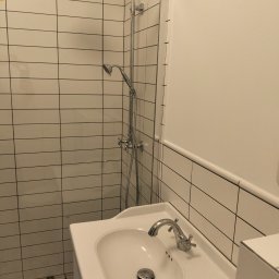 VOLODYMYR MYKHAILYK - Wykończona łazienka z białymi, poziomymi płytkami, chromowaną armaturą i umywalką w stylu retro na tle wzorzystej podłogi.