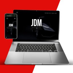 Ad Vision - Laptop i smartfon prezentują stronę internetową JDM Auto Detailing na czerwono-białym tle. Widoczny nagłówek strony i logo firmy.