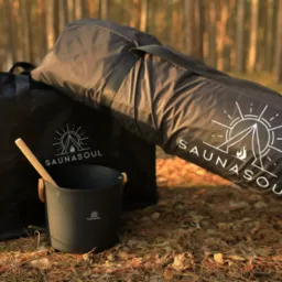 Zestaw akcesoriów do sauny mobilnej Saunasoul: torba, wiadro i chochla na tle leśnym. Minimalistyczny design z logo.