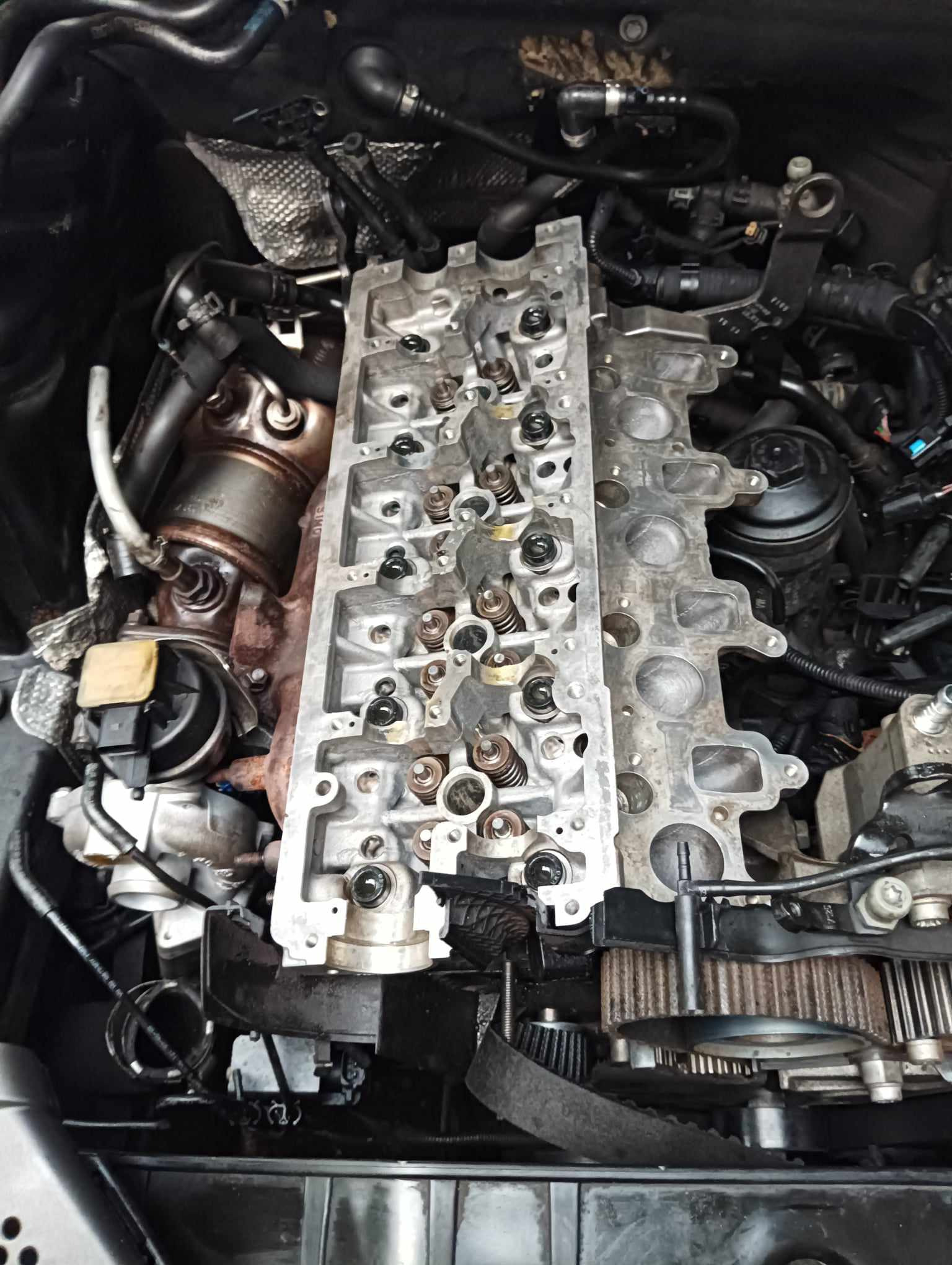 Głowica silnika z widocznymi sprężynami zaworowymi, element demontażu podczas naprawy, w warsztacie samochodowym. Z bliska, oświetlenie warsztatowe.