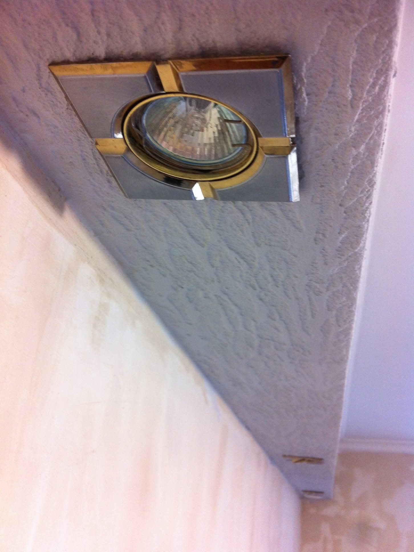 Światło sufitowe z ozdobną ramką w świeżo wykończonym suficie z fakturą, widok z dołu, podkreślający detale wykończenia i oświetlenie.