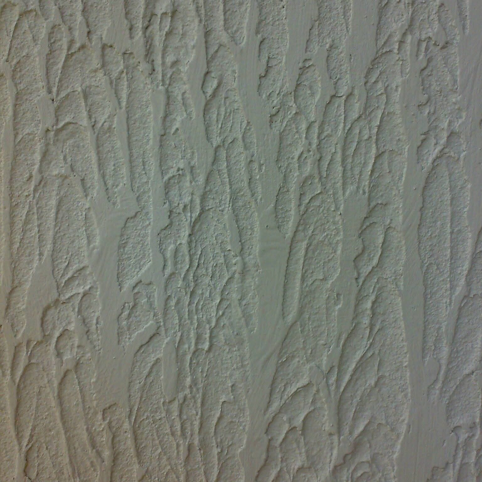 Zbliżenie na szpachlowaną ścianę z wyraźną fakturą. Pionowe, nieregularne wzory tworzą unikalny efekt dekoracyjny. Neutralna kolorystyka.