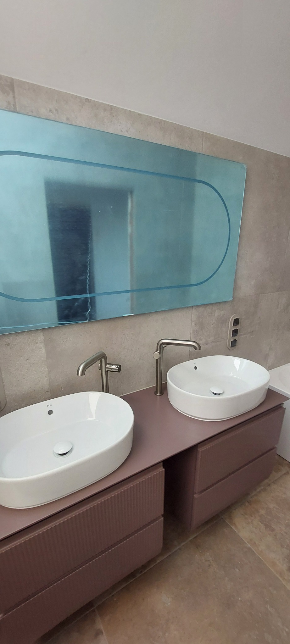 Nowoczesna łazienka w Gliwicach: dwie białe umywalki nablatowe z chromowanymi bateriami na szafce w kolorze pudrowego różu, nad nimi lustro w niebieskiej ramie.
