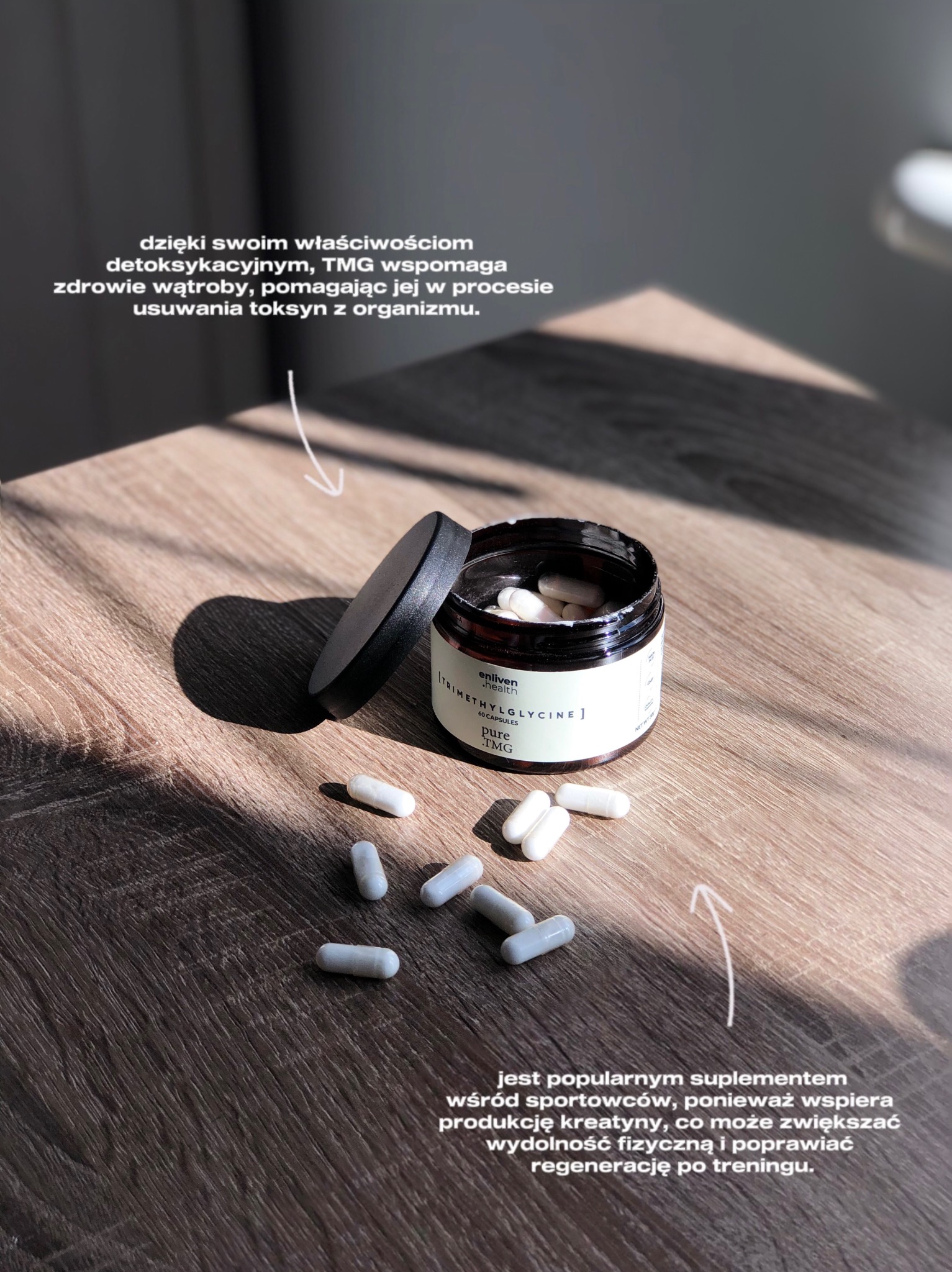 Zdjęcie suplementu Enliven.health w czarnym słoiczku z otwartym wieczkiem, kapsułki rozsypane na drewnianym blacie w naturalnym świetle. Minimalistyczna fotografia produktowa.